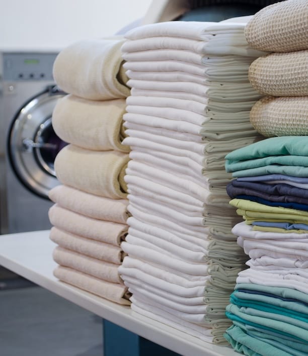 Neatly stacked piles of folded laundry in various colors, representing the end result both options are working toward and the question of which path to get there makes more sense