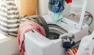 Tangled laundry spilling out of an open washing machine, capturing the chaos of a load that never seems to get finished