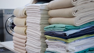 Neatly stacked piles of folded laundry in various colors, representing the end result both options are working toward and the question of which path to get there makes more sense