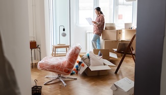 Person standing among moving boxes in a new apartment, representing the moment when laundry access becomes something that requires an actual plan for the first time