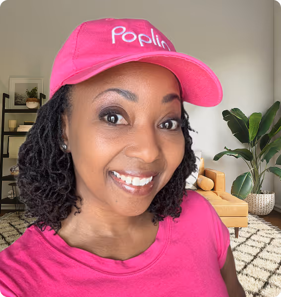 Smiling Poplin Laundry Pro wearing a pink Poplin hat and shirt, standing in a bright living room.
